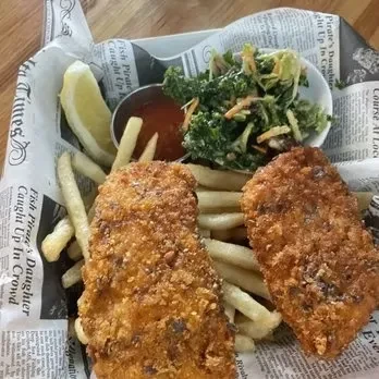 Fried fish and chips with slaw, sauce, and lemon on newspaper.