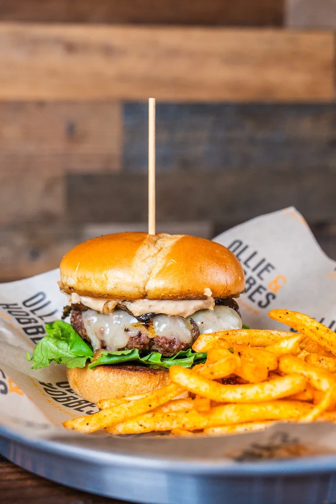 Cheeseburger with melted cheese, mushrooms, and fries on branded paper.