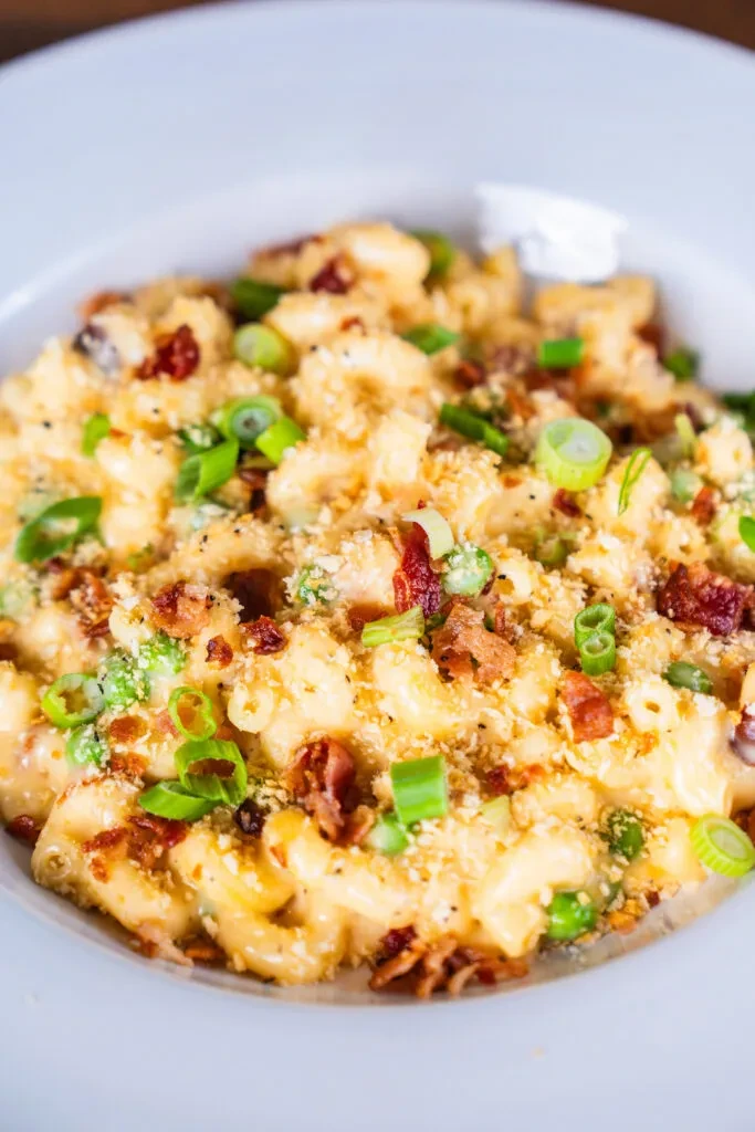 Macaroni and cheese with bacon, green onions, and breadcrumbs in a bowl.