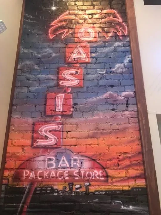 Mural with vertical OASIS neon, BAR PACKAGE STORE, sunset, and cityscape.