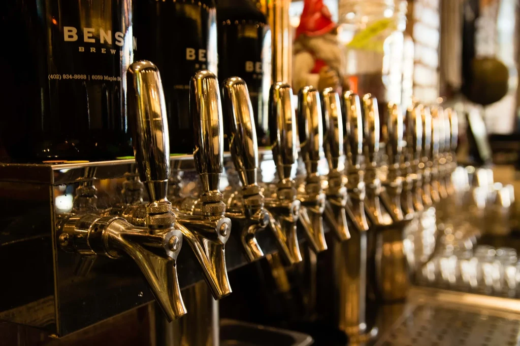 Row of shining golden beer taps and "BENSEN BREW" bottles.