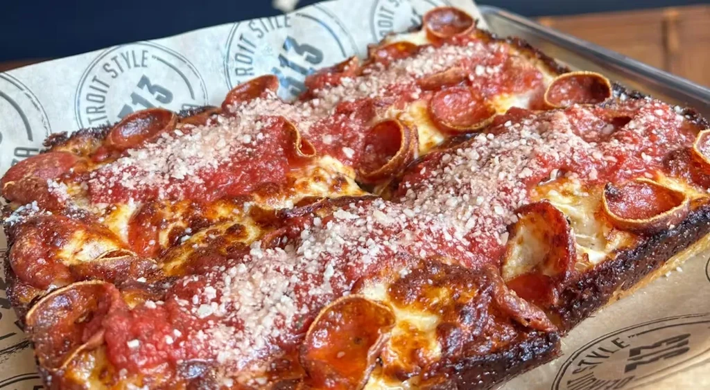 Rectangular Detroit-style pizza with pepperoni and cheese in a metal tray.