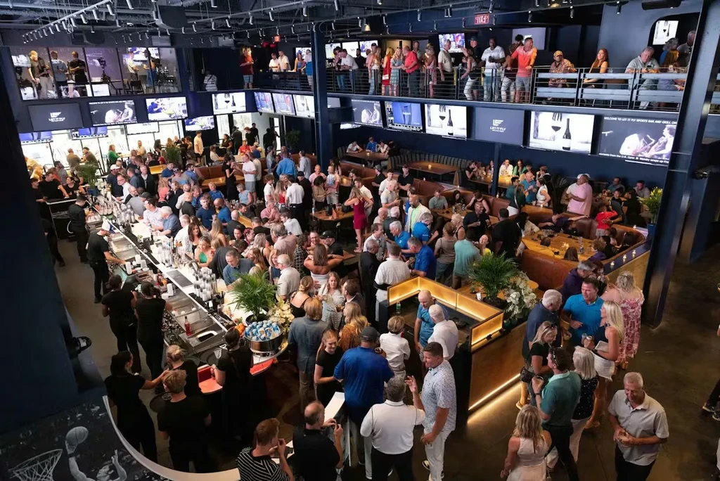 Lively, two-story modern sports bar interior filled with hundreds of patrons.