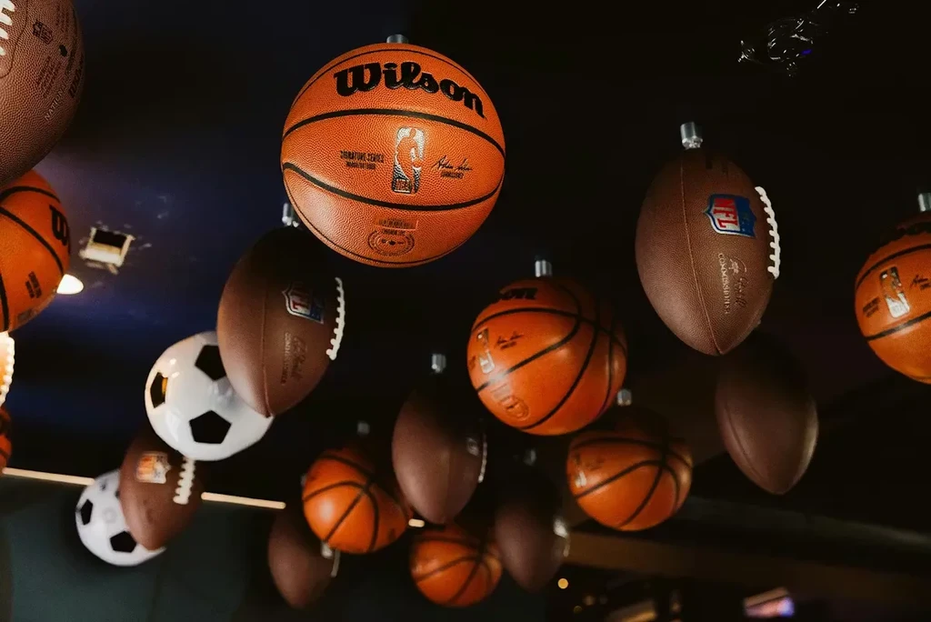 Branded sports balls suspended from a dark ceiling.