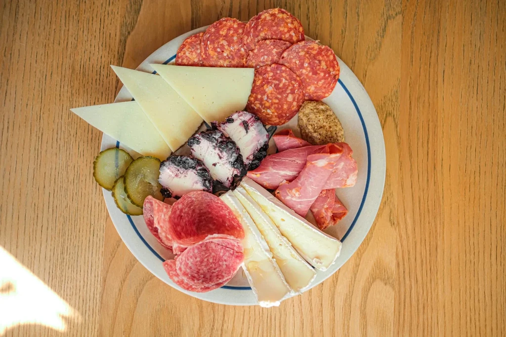 Overhead charcuterie board with various meats, cheeses, and pickles.