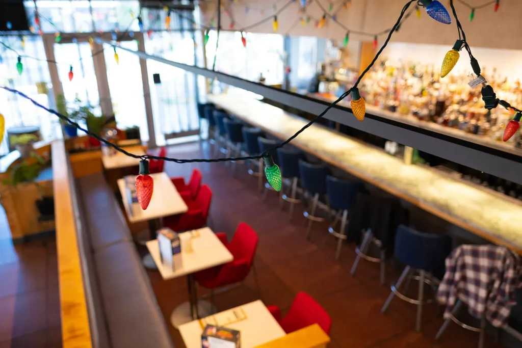 Multi-colored string lights decorate a modern restaurant's dining area and bar.