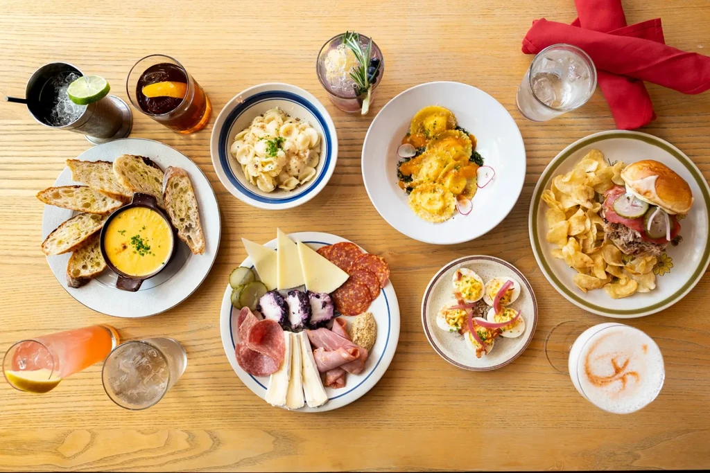 Top-down shot of diverse food and colorful cocktails on a wooden table.