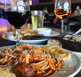 Close-up of spaghetti and meatballs with wine glasses in a restaurant.