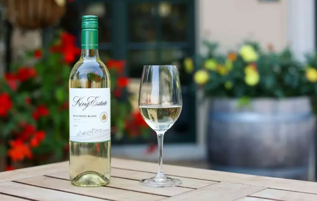 King Estate Sauvignon Blanc bottle and wine glass on outdoor wooden table.