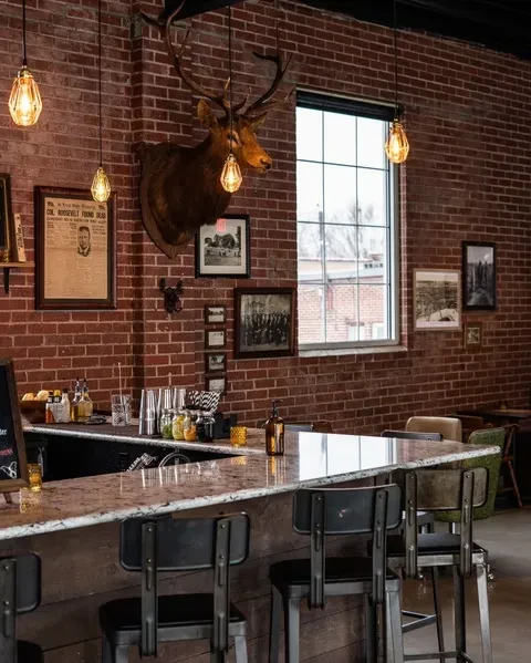 Rustic industrial bar with red brick walls and a prominent elk mount.