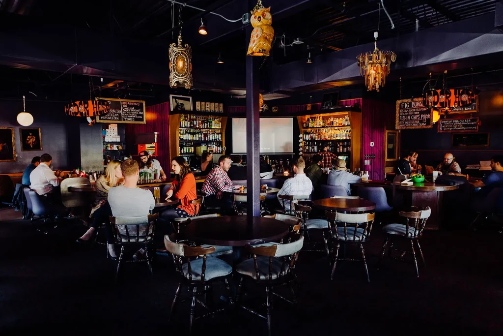 Dimly lit, eclectic restaurant interior with a bustling bar and diners.