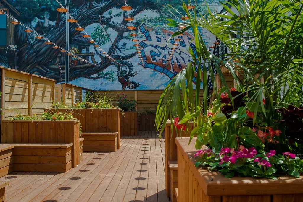 Vibrant outdoor patio with floral planters, wood deck, and beer garden mural.