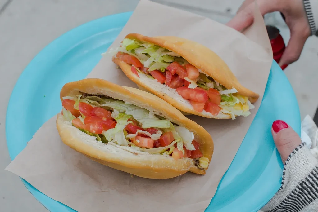 Two golden fried tacos filled with lettuce and tomatoes on a blue plate.