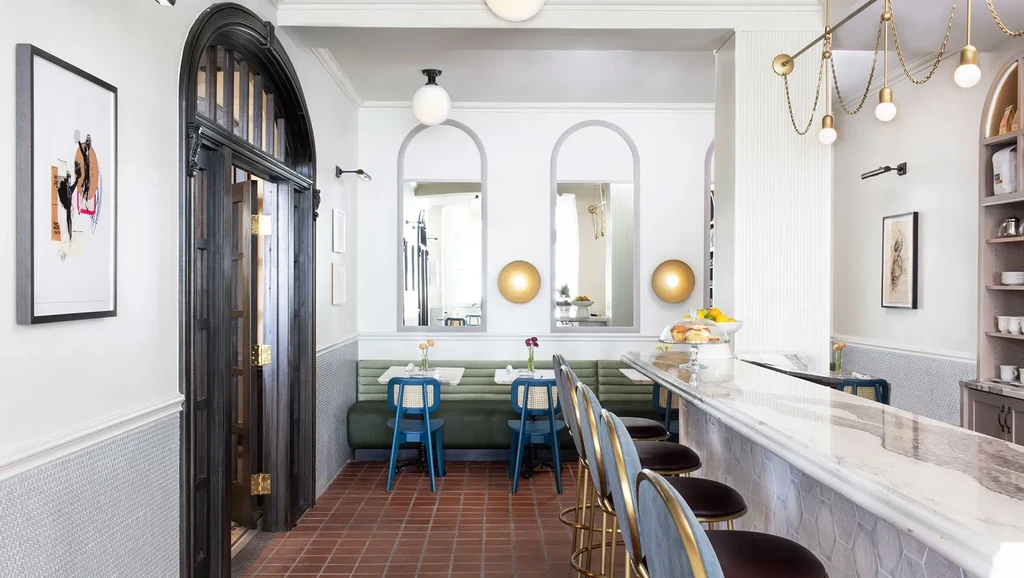 Stylish cafe interior with a white marble bar and olive green banquette.