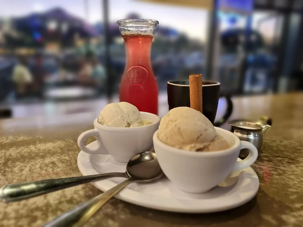 Close-up of ice cream cups and drinks on a brown table.