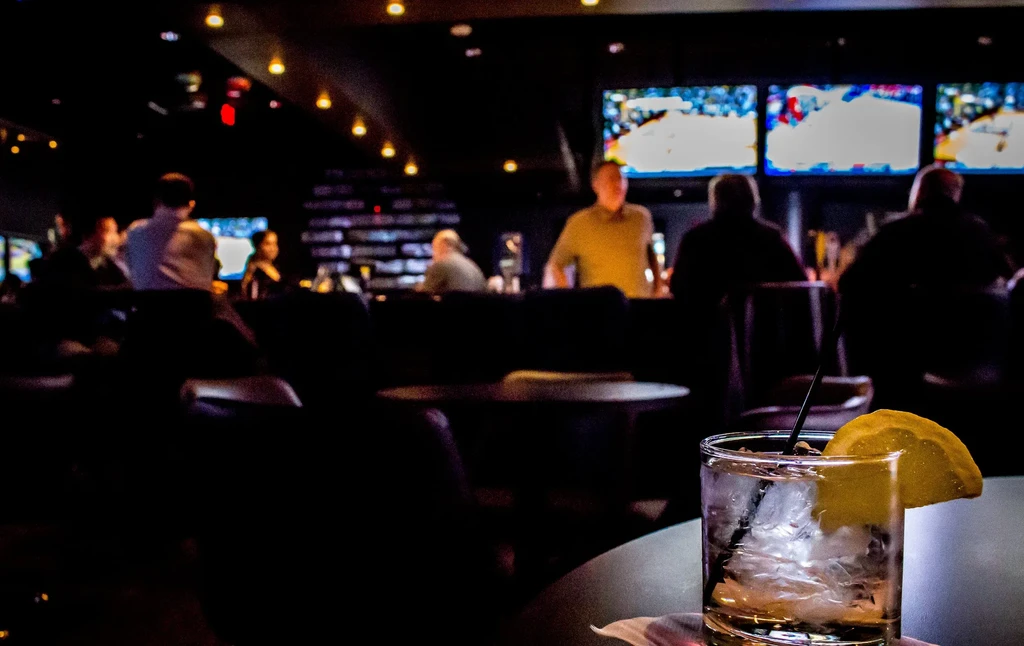 Drink with lemon and ice in a dark, lively bar.
