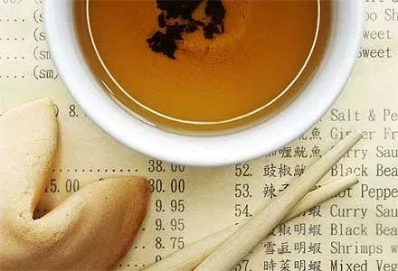 Tea bowl, fortune cookie, and chopsticks on an Asian menu.