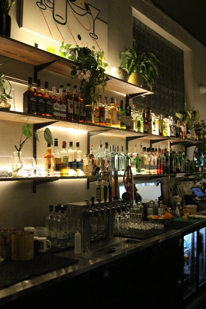A well-stocked bar interior with glowing liquor bottles and plants.