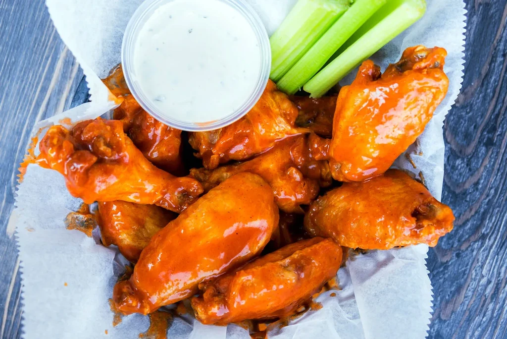 Close-up overhead: Basket of buffalo wings, celery, and dipping sauce.