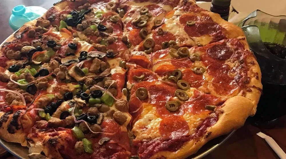 Pizza with half sausage and vegetables, half pepperoni and olives.