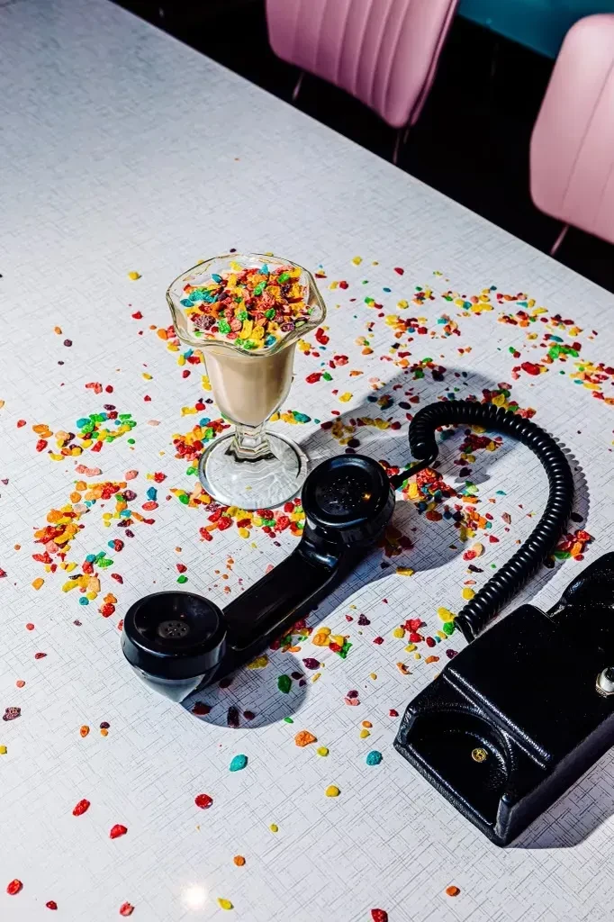 Retro diner scene: milkshake with colorful cereal, vintage telephone receiver.