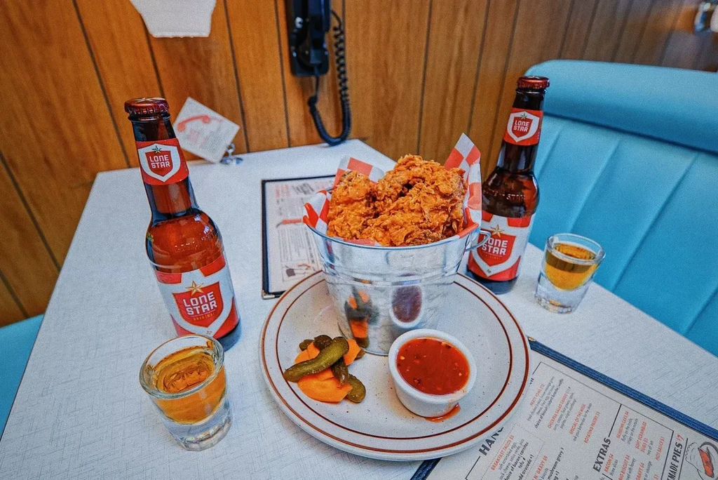Fried chicken, beer, and pickles on a retro diner table.
