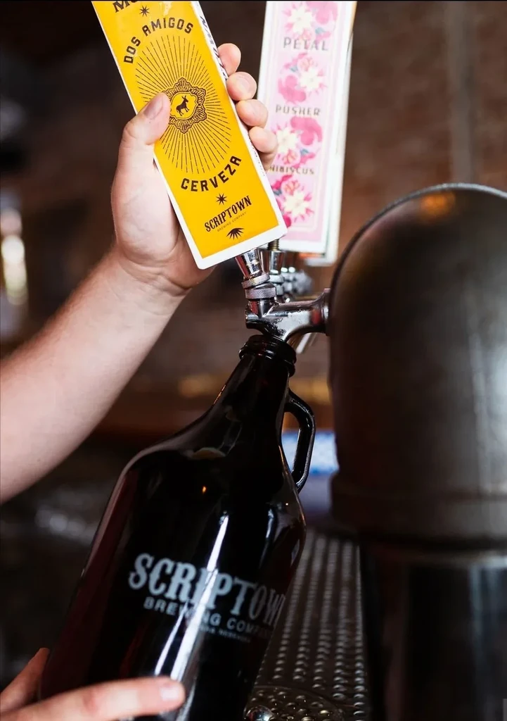 Close-up of hands filling a Scriptown growler from a beer tap.