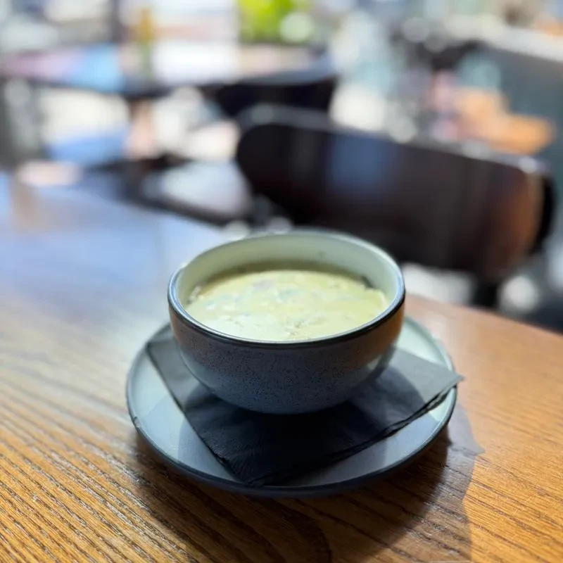 Creamy green dish in ceramic bowl with napkin on wooden table.