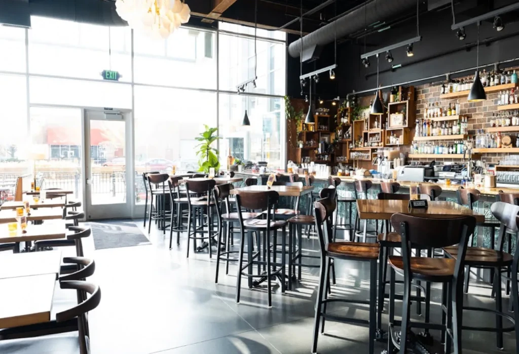 Chic, empty restaurant bar with varied seating and floor-to-ceiling windows.