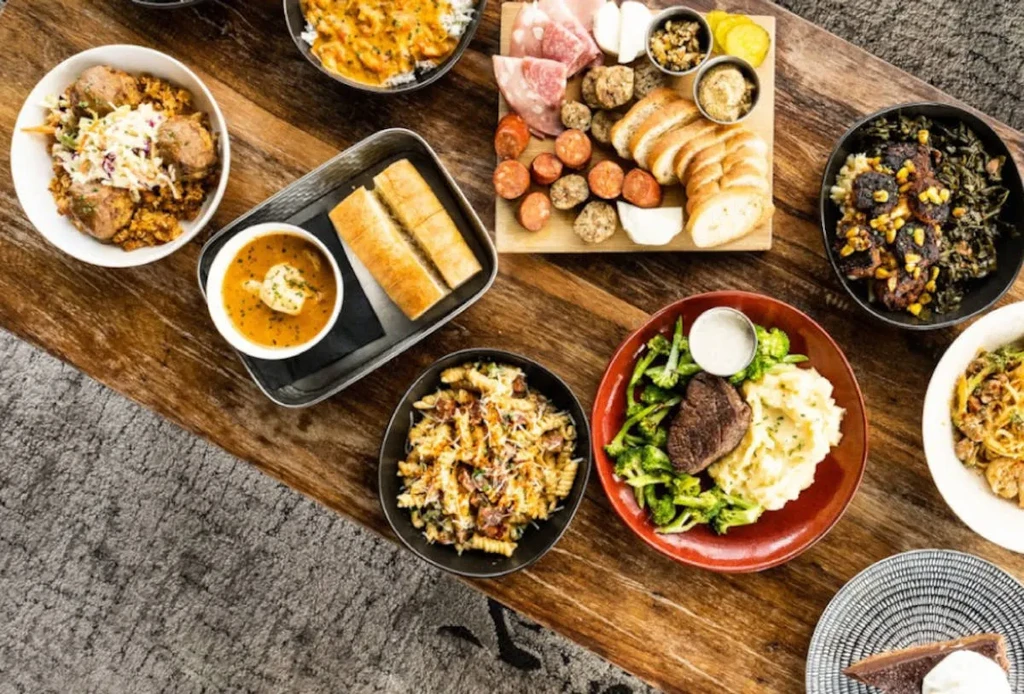 Overhead shot: large wooden table laden with diverse food dishes.