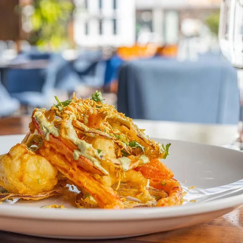 Golden-fried seafood tempura with green sauce, herbs, and a dumpling.