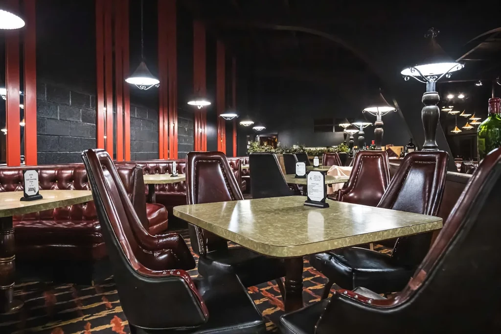 Warmly lit restaurant dining area with dark booths, black walls, and red accents.