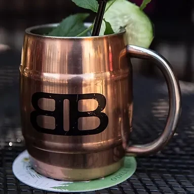 Barrel copper mug with BB logo, dark drink, mint, and cucumber.