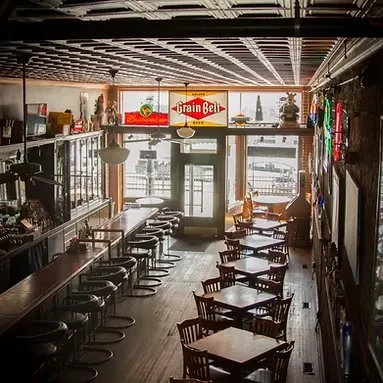 Vintage bar and restaurant interior with wooden bar, tables, and vintage signs.