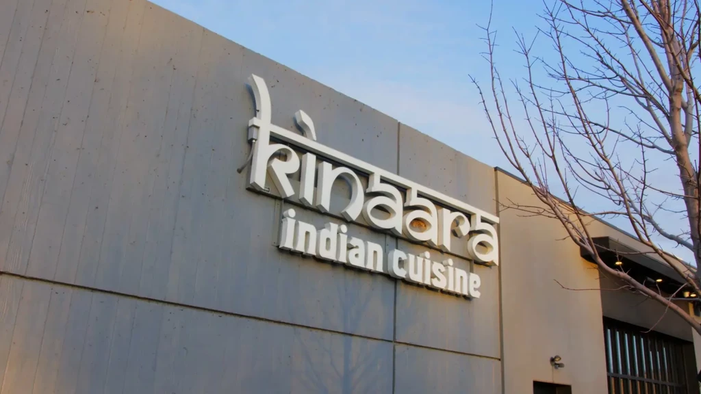 White 3D Kinaara Indian Cuisine restaurant sign on a grey wall.