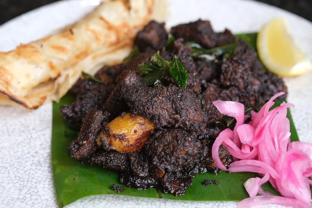 Spiced meat on banana leaf, with flatbread, pickled onions, lemon.