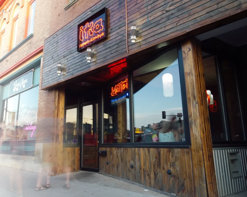 iika ramen + izakaya exterior with dark wood and red neon signs.