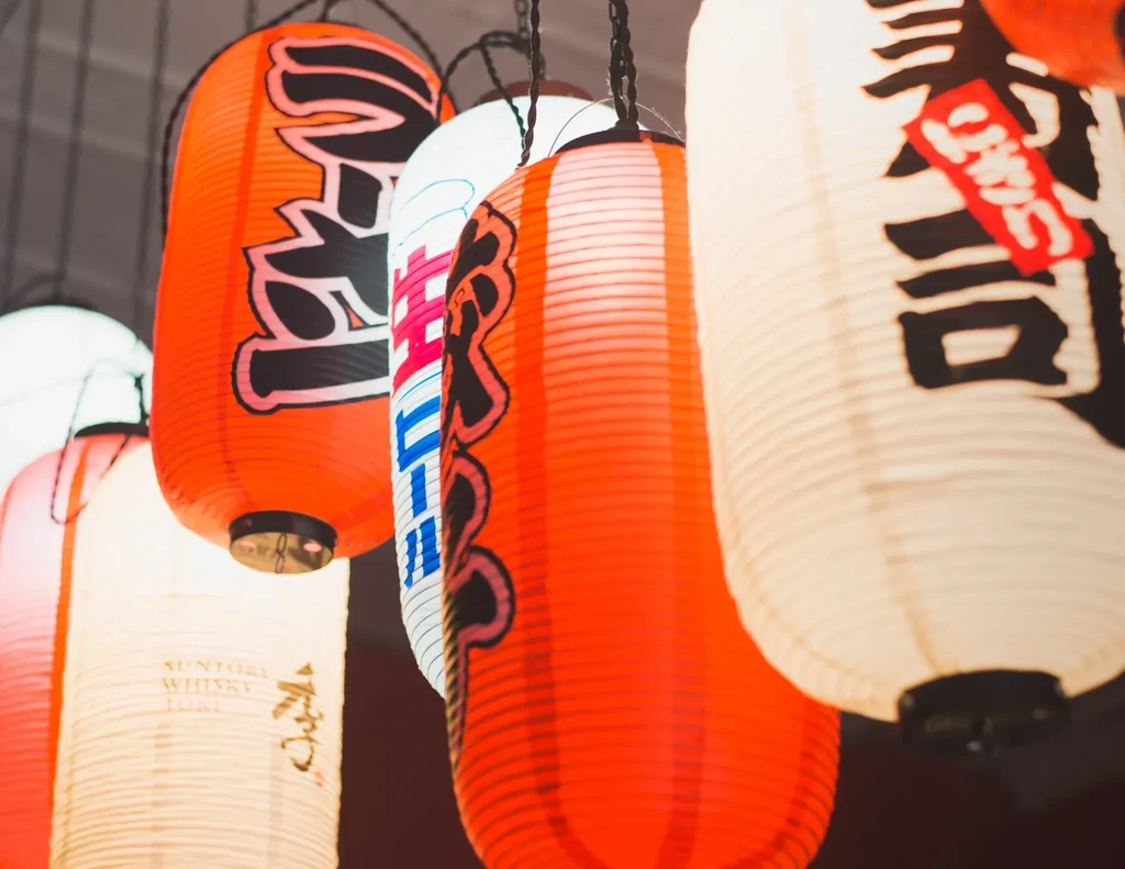 Illuminated Japanese lanterns hanging, one branded "SUNTORY WHISKY HIGHBALL."