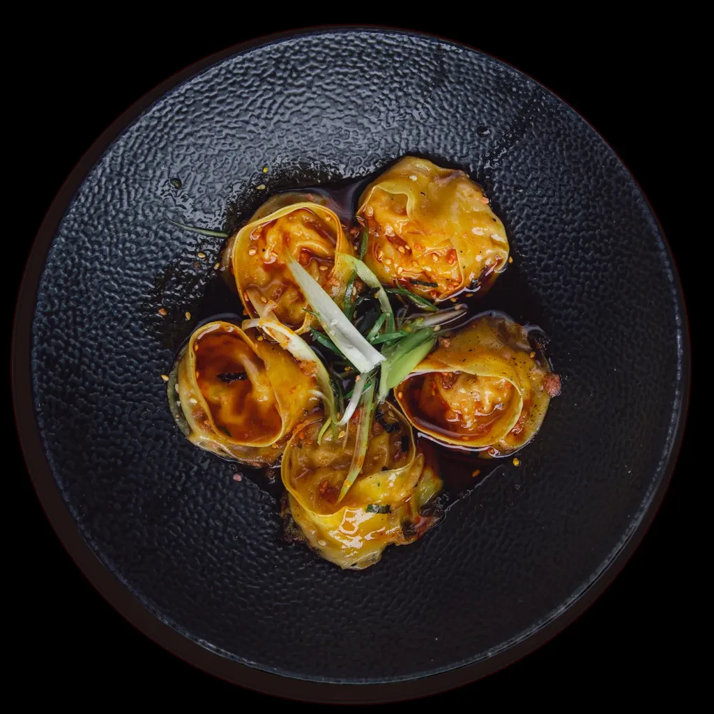 Five spicy golden wontons in chili oil, with sesame and green onions.