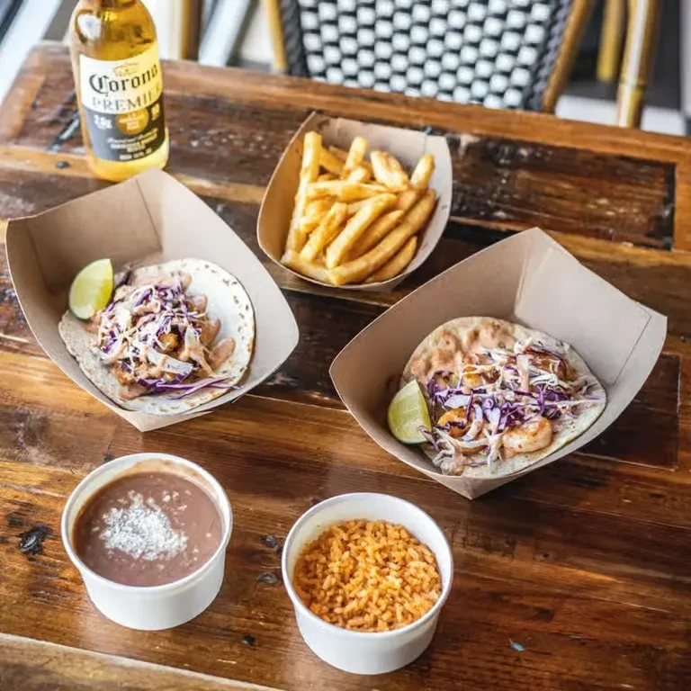 Overhead: tacos, fries, beans, rice, and Corona beer on wooden table.