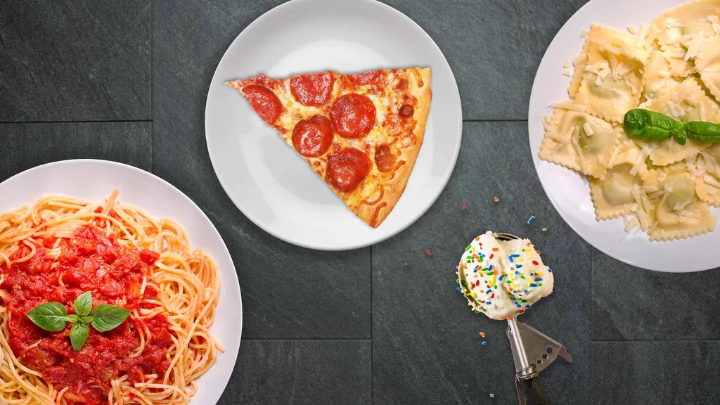 Flat lay of Italian-American spaghetti, pizza, ravioli, and sprinkled ice cream.