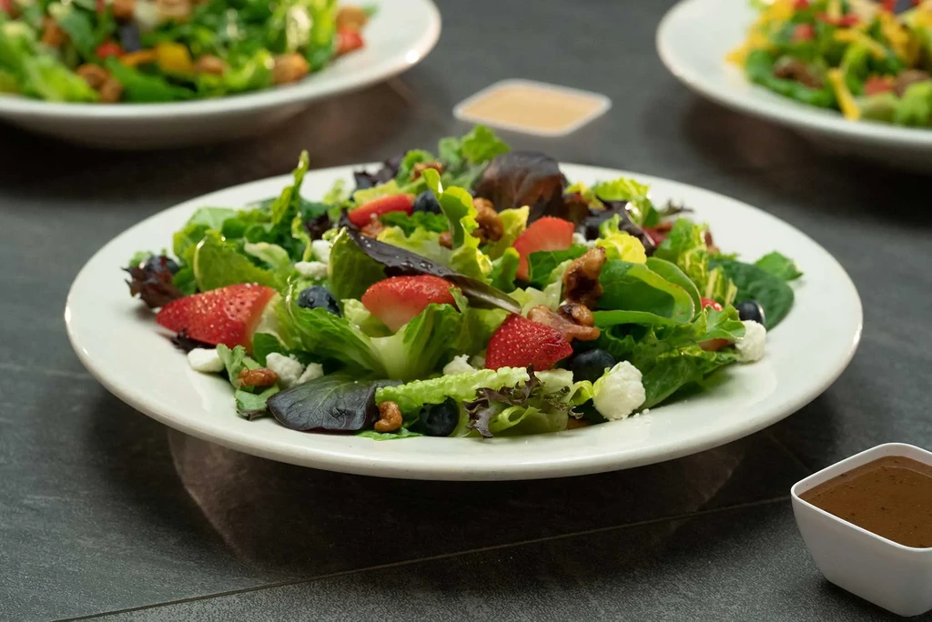 Vibrant salad with strawberries, blueberries, cheese, and walnuts.