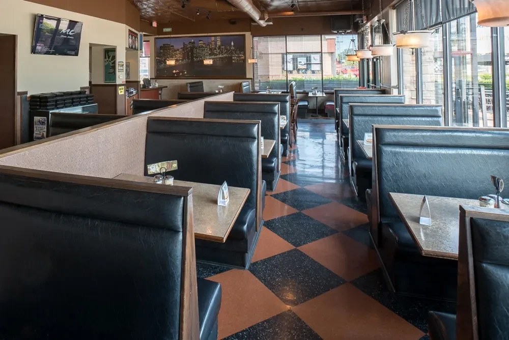 Empty casual dining restaurant interior with dark booths and checkerboard floor.