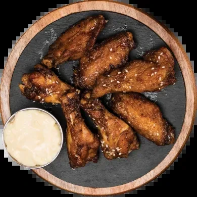 Glazed chicken wings with sesame seeds and dipping sauce on a slate plate.
