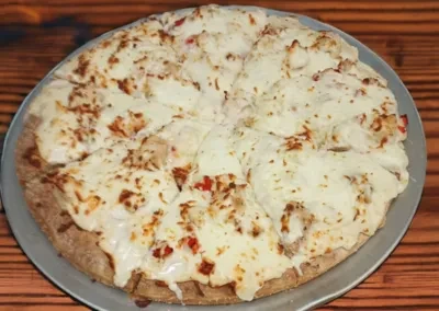 Round chicken and pepper pizza with melted cheese on a silver pan.