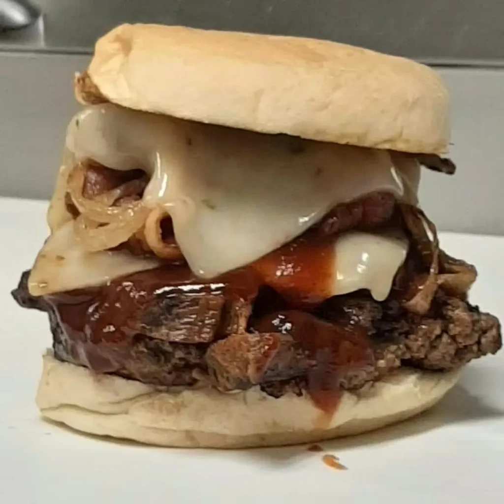 Close-up of a gourmet burger with melted cheese, caramelized onions, and pulled pork.