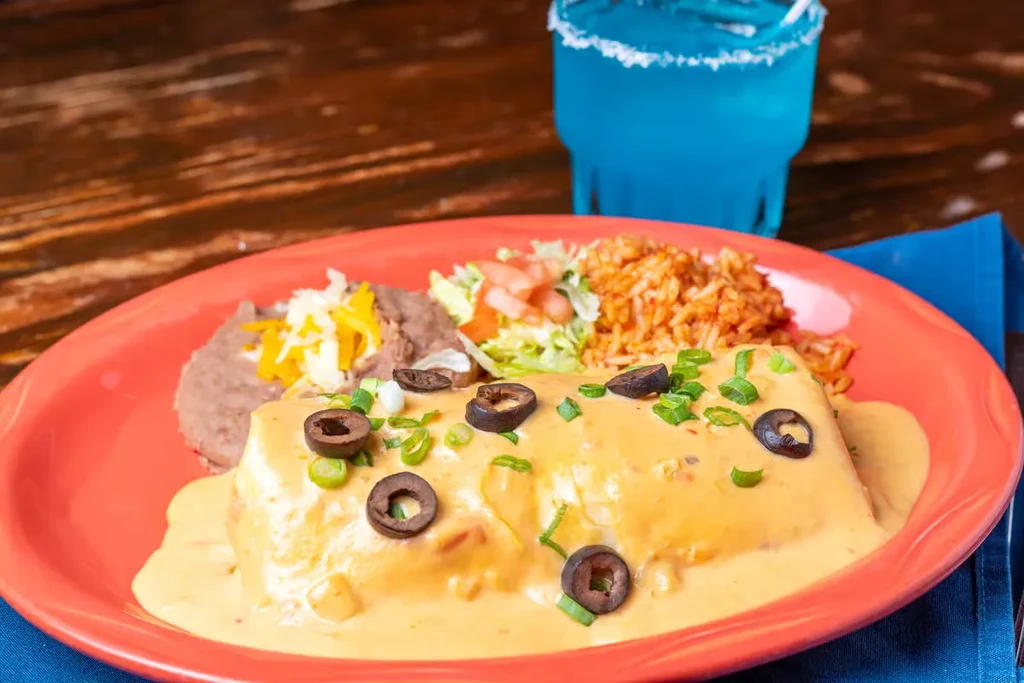 Enchilada plate with cheese sauce, refried beans, Mexican rice, and salad.