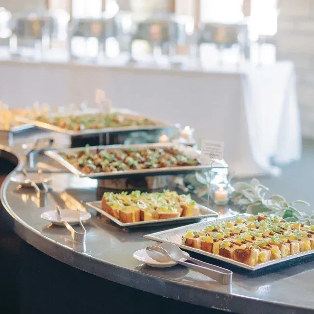 Well-arranged buffet line displaying platters of appetizers with various garnishes.