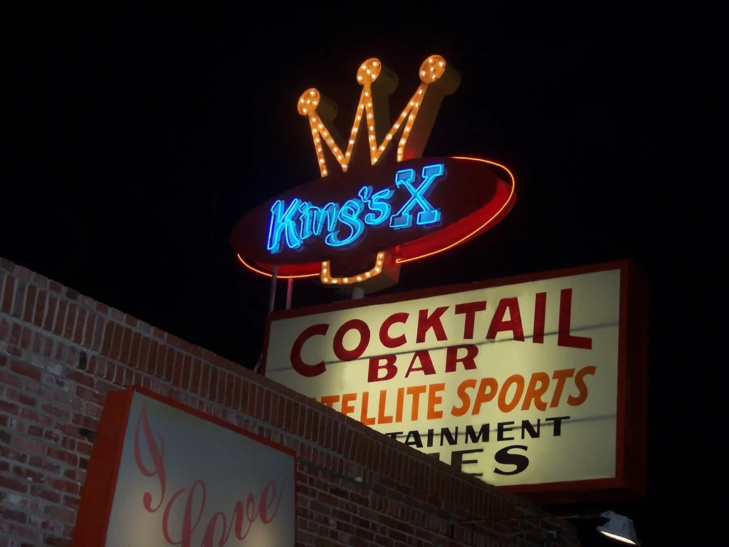 King's X neon and 'COCKTAIL BAR' lightbox signs at night.