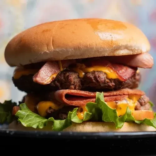 Stacked double-patty burger with melted cheese, crispy bacon, and lettuce.